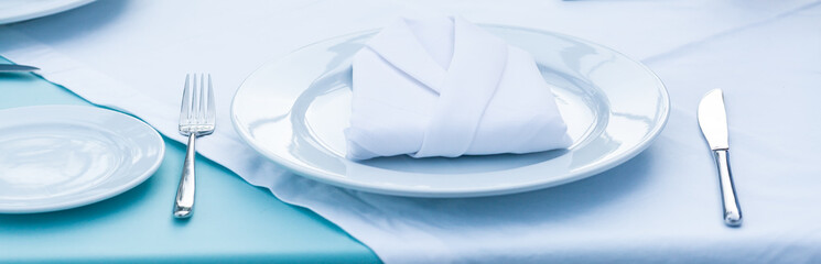 Plates and knives and forks placed on a table with napkins,White napkin, silver fork and knife on table set for dinner in a restaurant. Food concept. 