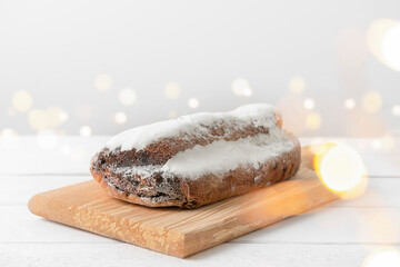 Christmas stollen cake on white wooden background with bokeh lights