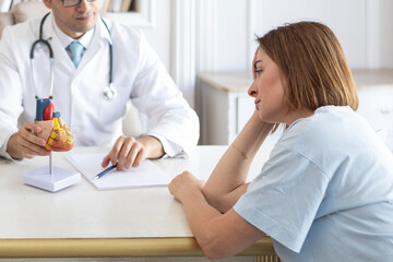 Obraz premium Portrait of young upset female patient and doctor cardiologist working in office of modern clinic
