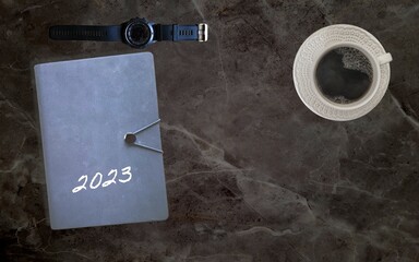 work table and office with cup of coffee, headphones agenda 2023 computer and clock