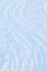 Close-up of fresh shiny snow on the ground on a sunny day, curved pattern. Viewed from above. Good as a winter season background. Abstract natural backdrop.