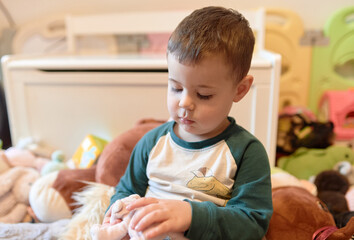 happy young boy playing among a mountain of soft plush toys