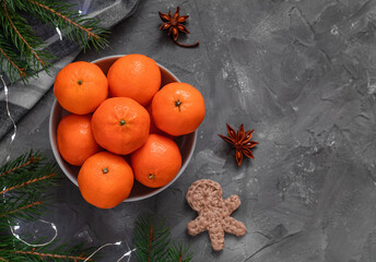 Tangerine, mandarine or clementine bowl on a gray background with fir tree branches, star anise and...
