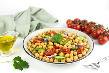 Chickpea salad with tomatoes, cucumbers, onions and olive oil on a white background. Selective focus. Oriental and Mediterranean cuisine.