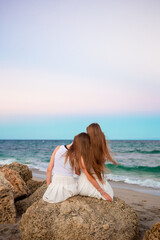 Fototapeta na wymiar Adorable girls with long hair enjoy sunset on the beach