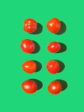 Spring pattern in red and green. Minimal background with ripe cherry tomatoes on harsh sunlight with dark shadow