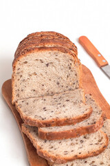 Fresh whole grain sliced bread close up on a wooden board on a white background.