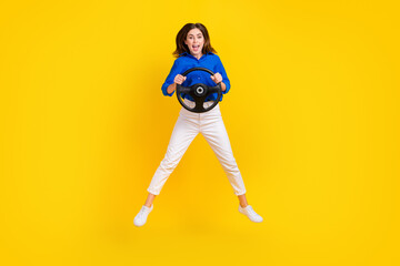 Fototapeta na wymiar Full length photo of charming excited lady wear blue shirt driving transport jumping high isolated yellow color background