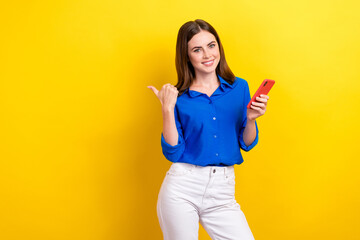 Photo of pretty charming lady wear trendy blue clothes arm direct empty space buy device shop sale isolated on yellow color background