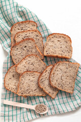 Fresh whole grain sliced bread with sunflower seeds and flax on a linen napkin on a white background. Healthy bakery product.