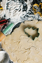 Cutting Christmas tree shapes into freshly rolled sugar cookie dough