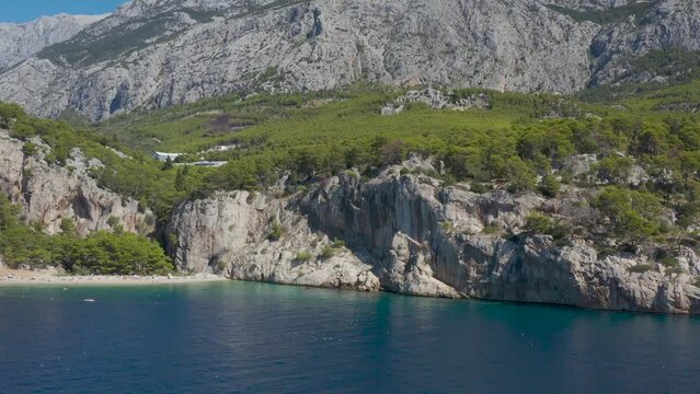 Beautiful beach among mountains and forest. Croatia. Makarska Riviera. Adriatic Sea lagoon with clear blue water and pine aroma. Drone video. Vacation . Many people. Nugal Beach