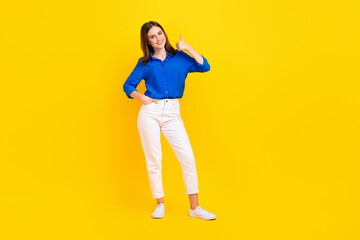 Fototapeta na wymiar Full length photo of cute confident girl dressed blue shirt dancing showing thumb up empty space isolated yellow color background