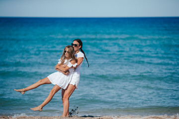 Young happy mother and and her daughter having fun on the beach