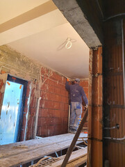 Workers plaster walls in a new house