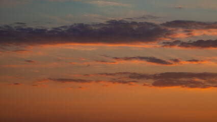 Fototapeta na wymiar Soft deep orange sky, illuminated clouds at bloody sunset as a background.