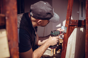 Handyman screwing a door hinge in the wooden door frame. Home renovation