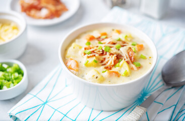 Fresh hot chowder soup with fried bacon slices and shredded cheese in a bowl