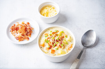 Fresh hot chowder soup with fried bacon slices and shredded cheese in a bowl