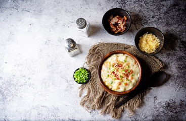 Fresh hot chowder soup with fried bacon slices and shredded cheese in a bowl
