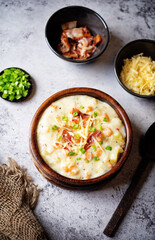 Fresh hot chowder soup with fried bacon slices and shredded cheese in a bowl