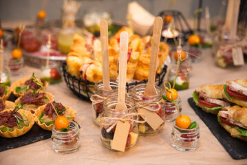 Catering in jars with wooden forks. lots of cold snacks, croissant sandwiches, tartlets, canapés in jars