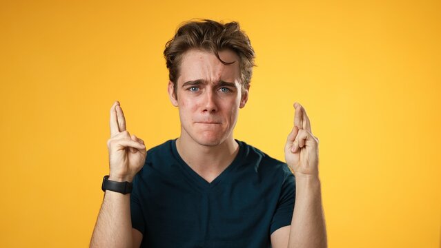 Young Worried Pleading Man 20s Hold Hands Folded In Prayer Begging About Something Making Wish Keep Fingers Crossed Isolated On Yellow Background Studio. People Lifestyle Concept 