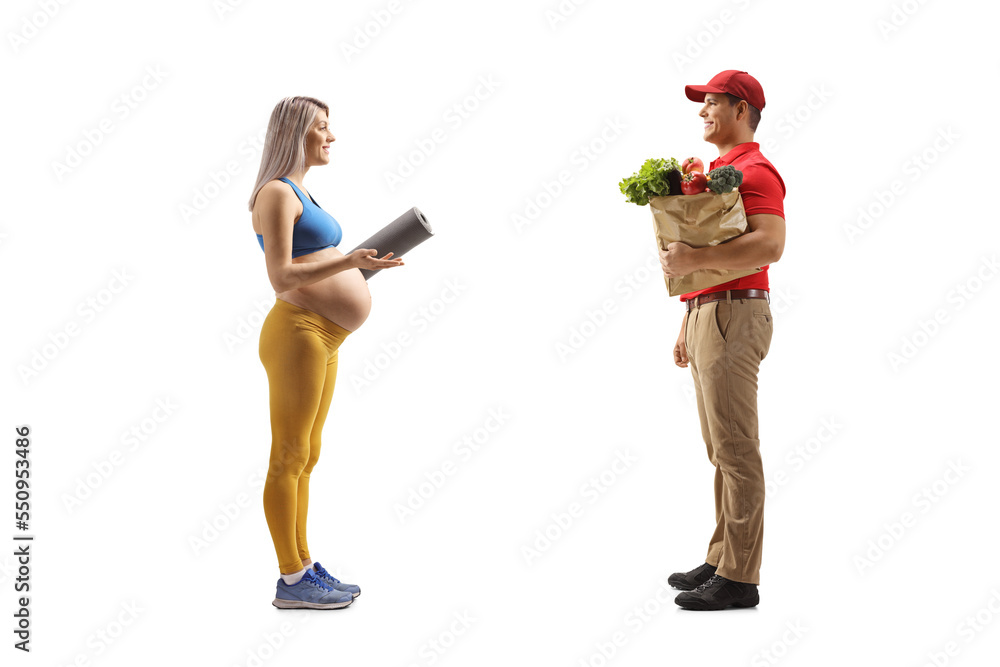 Wall mural Full length profile shot of a pregnant woman talking to a delivery man with a grocery bag