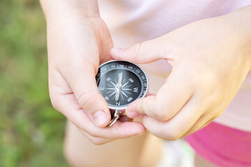 School age child, girl holding a simple compass in hands, seeking north, outdoors shot, object detail, closeup, shallow dof. Finding the right way, right direction, guidance, education and decisions © Tomasz