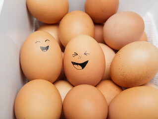funny laughing chicken eggs in a tray with other eggs. selective focus