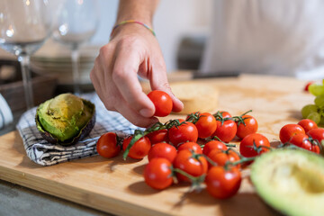 Man hand picking cherry tomato for his breakfast preparation