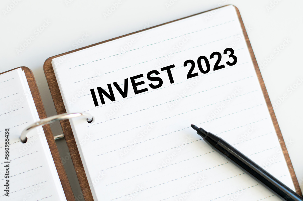 Aufkleber invest 2023 words on a sheet of open notepad on the table