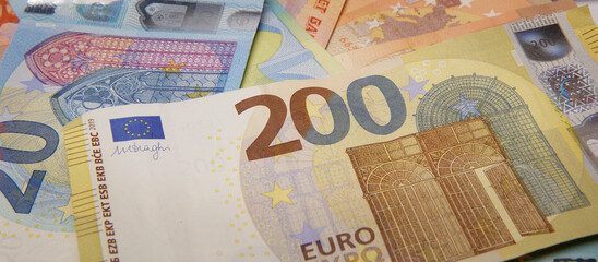 two hundred euros in the foreground and a few more euro notes. selective focus.