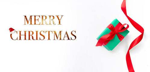 green box with a gift tied with a red ribbon on a white background and the inscription Merry Christmas. High quality photo