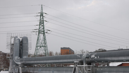 pipeline and power line in the city in winter against the gray sky