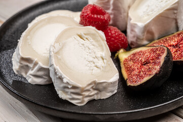 French organic matured white goat cheese with white rind close up served with fresh raspberries and figs