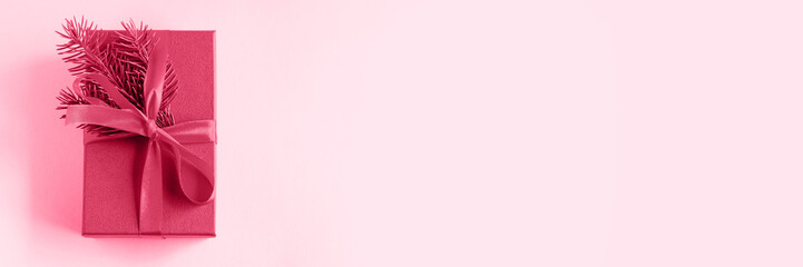 Gift box with a Christmas tree branch of the color Viva Magenta. Color of the year 2023.