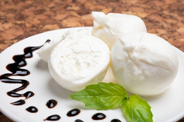 Eating of fresh handmade soft Italian cheese from Puglia, white balls of burrata or burratina cheese made from mozzarella and cream filling served with balsamico cream