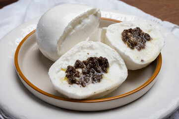 White balls of Italian soft cheese Mozzarella di Bufala Campana stuffed with black truffles mushrooms