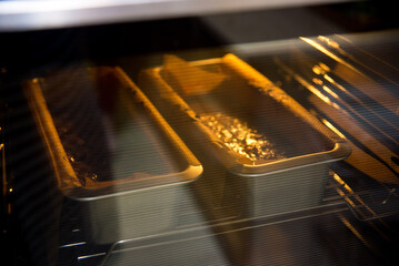 two metal molds with dough stand in the oven and bake