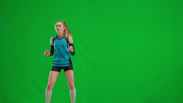 Young woman in sports excitement waiting for the ball to be served during game of volleyball. Athlete female volleyball player hitting the ball on green screen chroma key.