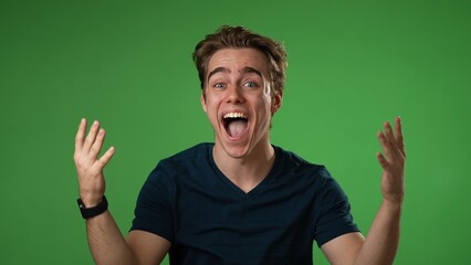 Naklejka premium Portrait of excited, surprised smiling young hipster man 20s gives thumbs up smiling isolated on green screen background studio in slow motion