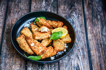   Allasca Pollock Fish  Bites in a crispy Tempura  Batter.Fish and chips .Close up of   crispy breaded  deep fried fish fingers with breadcrumbs s erved with remoulade sauce and  lemon