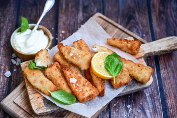   Allasca Pollock Fish  Bites in a crispy Tempura  Batter.Fish and chips .Close up of   crispy breaded  deep fried fish fingers with breadcrumbs s erved with remoulade sauce and  lemon