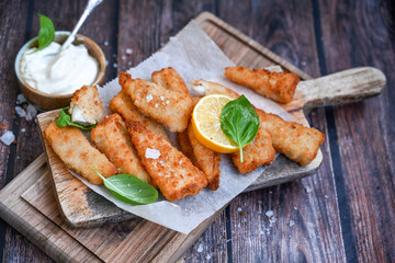   Allasca Pollock Fish  Bites in a crispy Tempura  Batter.Fish and chips .Close up of   crispy breaded  deep fried fish fingers with breadcrumbs s erved with remoulade sauce and  lemon