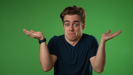 Portrait of happy young man 20s shrugging shoulders and gesturing I do not know isolated on green screen background in slow motion