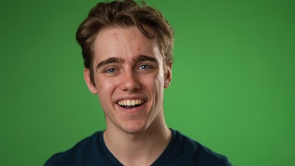 Fototapeta premium Closeup slow motion portrait of smiling happy young hipster man 20s isolated on green screen chroma key background with in studio