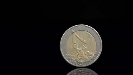 Two Euro coin spinning on black background. Falling or rising euro currency. Close up slow motion shot - Powered by Adobe