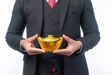 Hands of man suit holding Chinese New Year Gold Ingot standing over isolated white background Guy...
