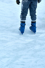 feet in blue skates on an ice rink. Hobbies and sports. Vacations and winter activities. Vertical shot
